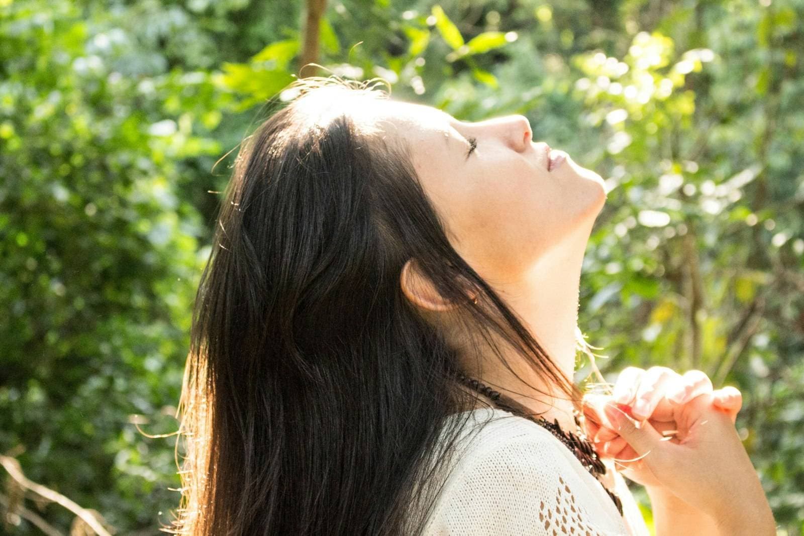 Woman with eyes closed breathing in fresh forest air, detox peptides at PeRx