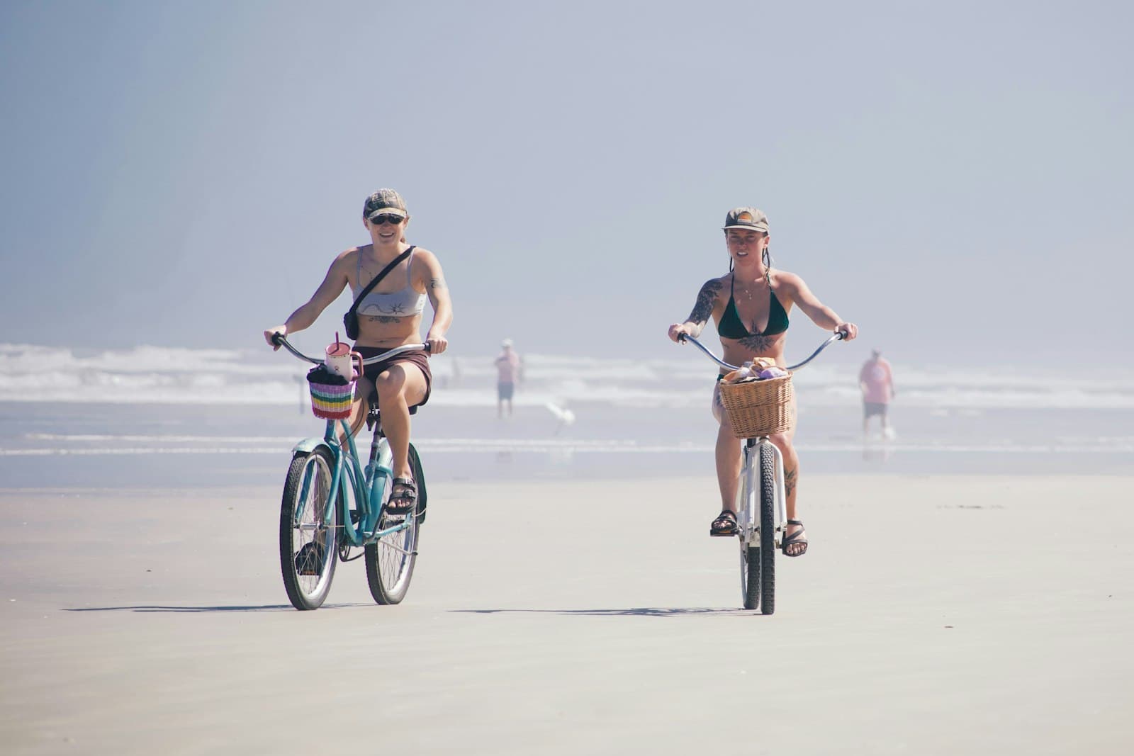 Two women riding cruiser bikes on the beach, fat loss peptides at PeRx