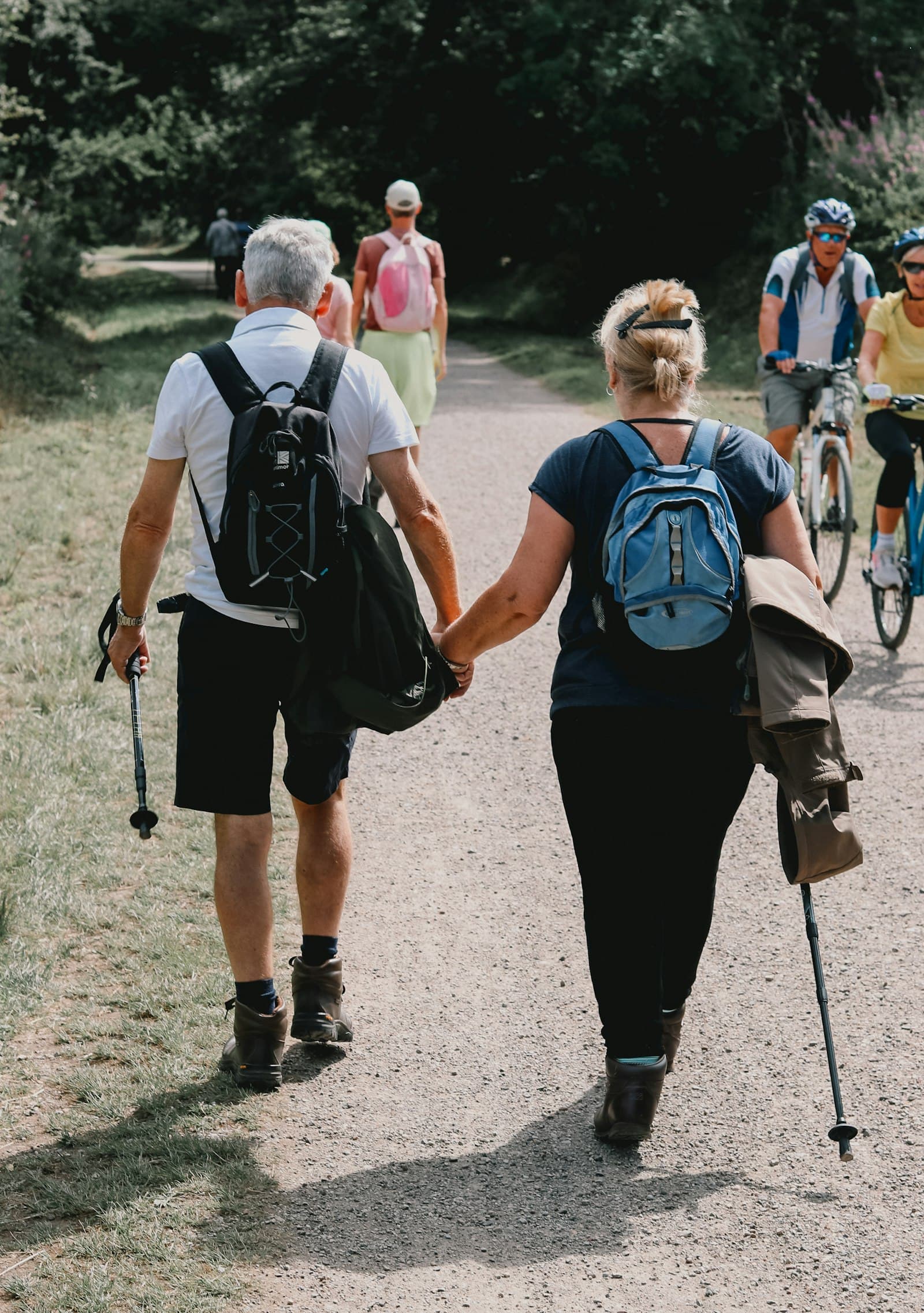Active older couple walking a sunlit trail hand in hand, longevity peptides at PeRx