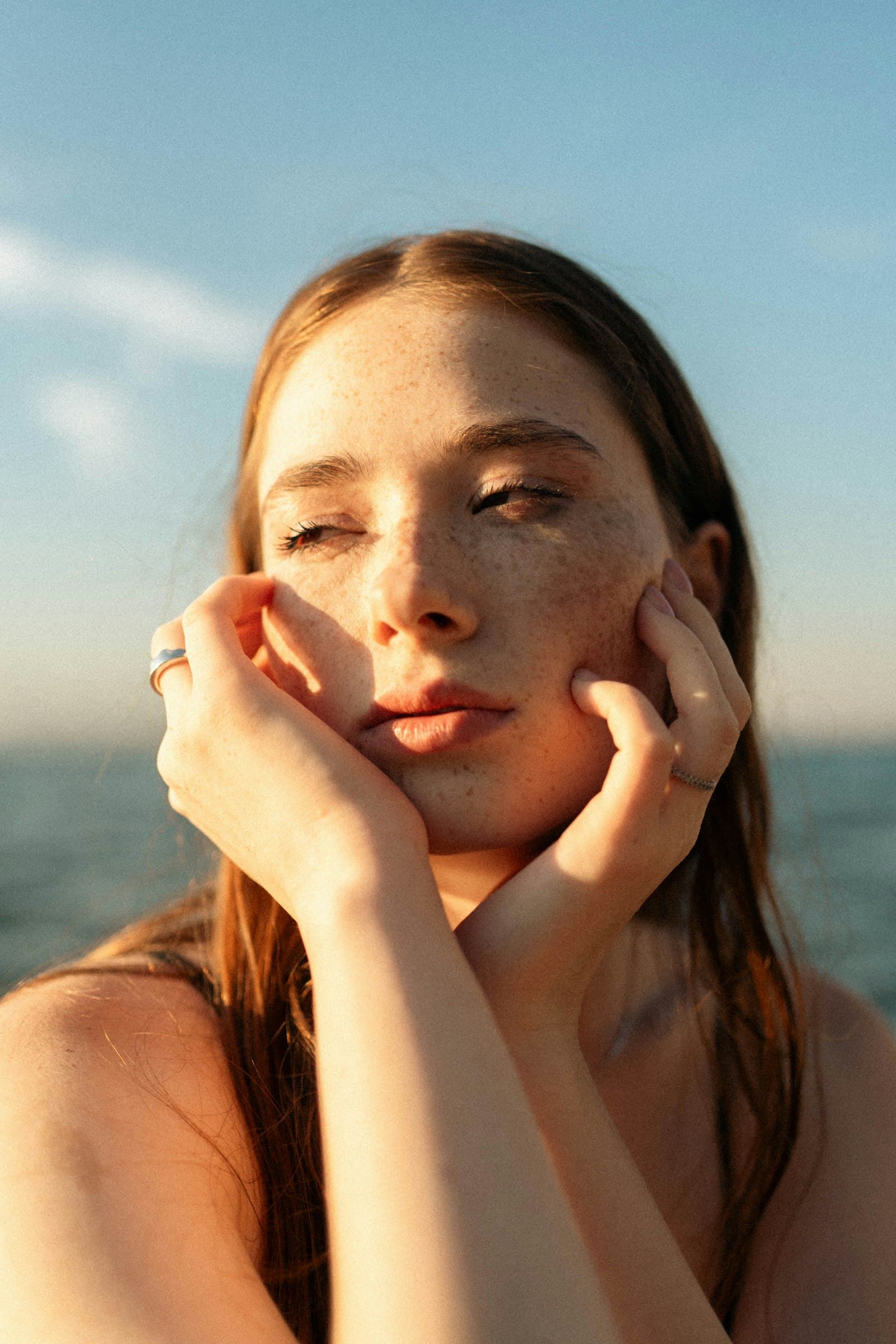 Woman with freckles and glowing skin in golden-hour light, peptides for skin at PeRx