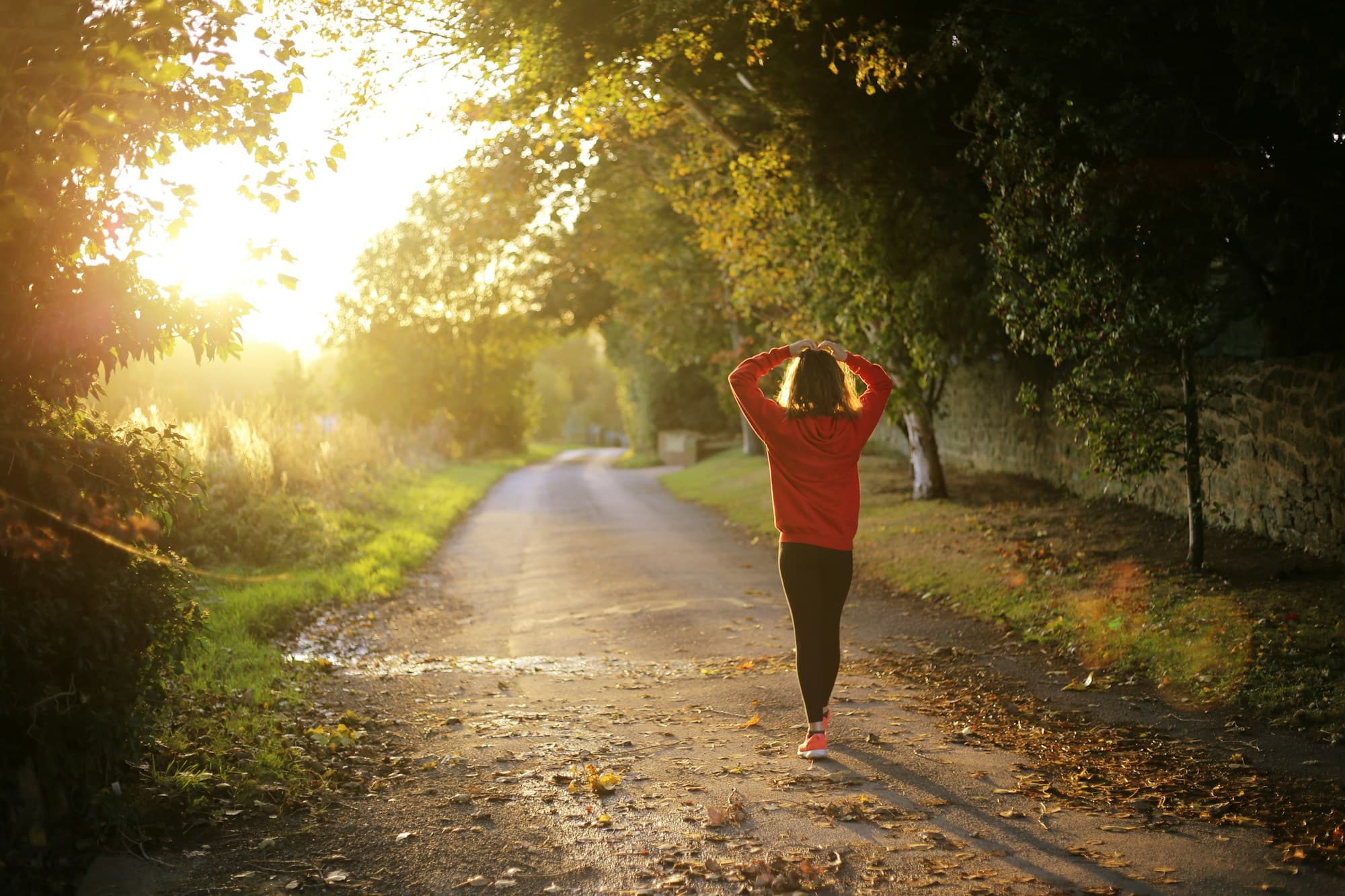 Woman walking a sunlit tree-lined path, peptides for weight loss at PeRx