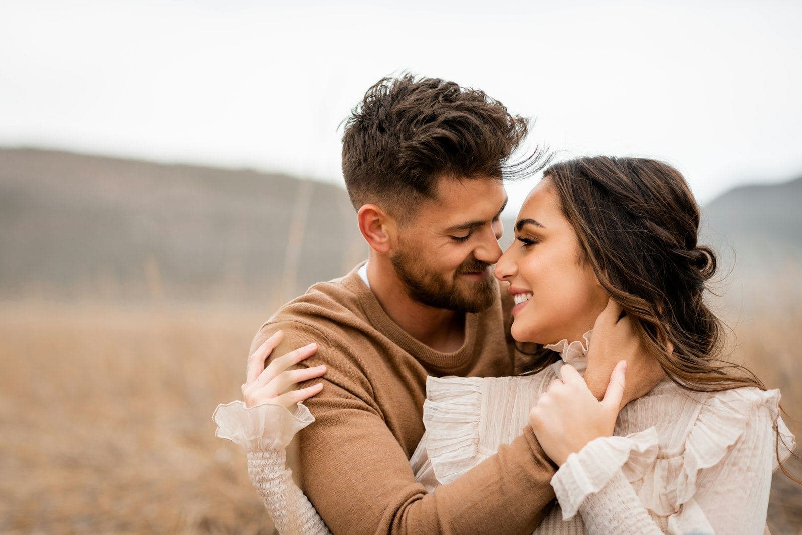 Couple embracing and smiling at each other in a golden field, peptides for sexual health at PeRx